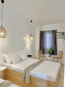 1 dormitorio con 1 cama con sábanas blancas y sillas en NEW Modern Suite near Airport & Beach en Sudtungan