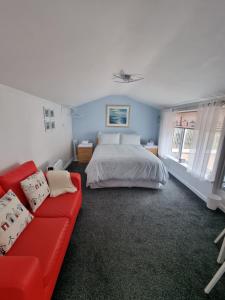 een slaapkamer met een bed en een rode bank bij The Garden Suite Holt in Holt