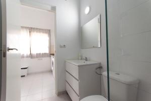 a white bathroom with a toilet and a sink at Piso Reformado in Vecindario