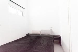 a bed in a white room with a window at Piso Reformado in Vecindario