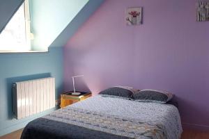 um quarto com uma cama e uma parede roxa em Guingamp centre : grand appartement lumineux em Guingamp