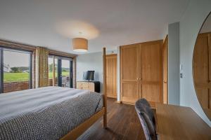 a bedroom with a bed and a desk and a window at Woodland Barn in Durham