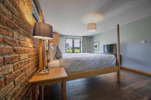 1 dormitorio con cama y pared de ladrillo en Woodland Barn, en Durham