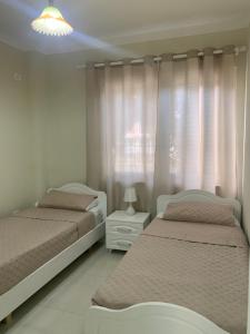 een slaapkamer met 2 bedden en een raam met gordijnen bij Ferienwohnung Golem (Durres) in Golem