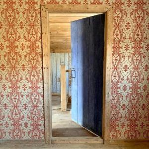 una puerta de madera abierta en una habitación con papel pintado en Husmannsplassen Havrebakken på Helgøya, en Ringsaker