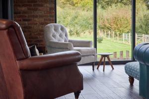 a living room with two chairs and a chair and a table at Woodland Barn in Durham