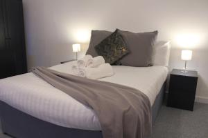 1 dormitorio con 1 cama con 2 toallas y 2 lámparas en Comfy Studio with Transport Links to MCR en Heywood