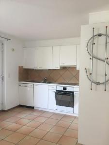 a kitchen with white cabinets and a tile floor at Les Rossets in Boudry