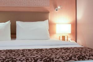a bedroom with a large bed and a lamp at Toledo Amman Hotel in Amman