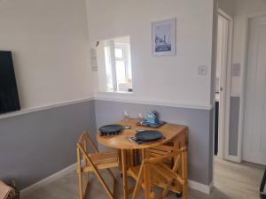 a wooden table with two chairs and a table with a window at Private 2 bedroom house close to the beach in Paignton
