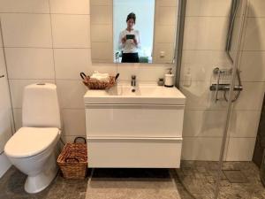 a woman taking a picture of a bathroom with a toilet at Cozy modern studio apartment stay in Falkenberg