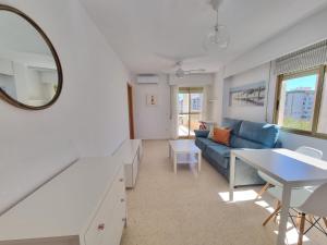 ein Wohnzimmer mit einem blauen Sofa und einem Spiegel in der Unterkunft BONITO APARTAMENTO EN PLAYA DE GANDIA in Playa de Gandia