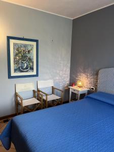 a bedroom with a blue bed and two chairs at Residence Gli Ulivi in Castion Veronese