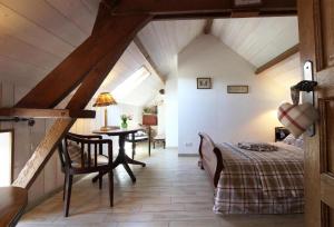 a attic bedroom with a bed and a table at Gîte La Bourgetterie Fontenay sur Mer in Fontenay-sur-Mer