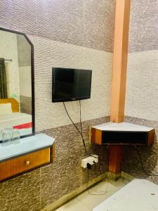 a bathroom with a tv and a sink and a mirror at Hotel Bengal in Kolkata