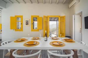 un comedor con una mesa blanca y armarios amarillos en Serenity Beach Villa - Port View, en Livadakia