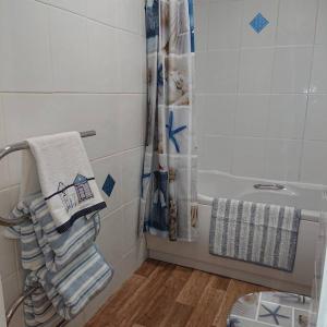 La salle de bains est pourvue d'une douche, d'une serviette et d'une baignoire. dans l'établissement Stylish 2 bed flat at Camber Sands, à Camber
