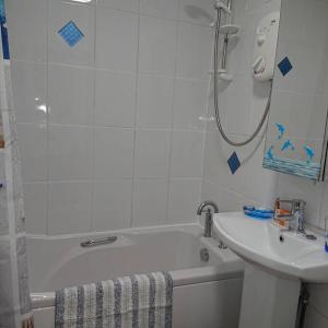 een badkamer met een bad, een wastafel en een douche bij Stylish 2 bed flat at Camber Sands in Camber