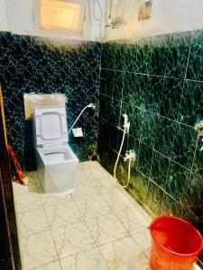 baño con aseo y pared de azulejos verdes en Hotel Bengal en Calcuta