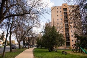 a sidewalk in a park next to a tall building at Firpo Apartman in Eger
