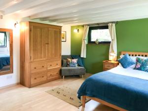 a bedroom with green walls and a bed and a chair at Little Fursdon Apartment in Merrymeet