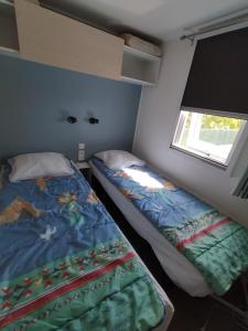 a small bedroom with a bed and a window at Mobil home Vendée in Saint-Jean-de-Monts
