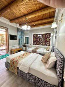 a large bedroom with two beds and a television at Grand Nodirbek Boutique Hotel in Bukhara