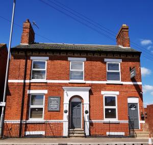 an old red brick building with a black door at Valletta House Holiday Apartments in Skegness