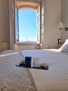 een bed met een dienblad met twee kaarsen en een raam bij Hôtel restaurant Clos des Sullys in Montclus