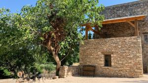 a stone building with a chair next to a tree at Hôtel restaurant Clos des Sullys in Montclus