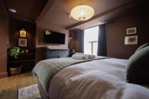 ein Schlafzimmer mit einem großen Bett und einem TV in der Unterkunft The Silk Rooms, at The Freemasons Inn in Knutsford
