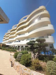 un grand bâtiment blanc avec des buissons devant lui dans l'établissement Happy Place Apartament, à Arenales del Sol