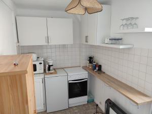 uma cozinha com electrodomésticos brancos e azulejos brancos em location appartement 100 m de la plage em Pénestin