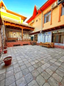 a courtyard of a building with benches and tables at Hotel Nurafshon Boutique in Bukhara