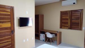 a room with a tv and a chair in a room at Hotel do Carmo in Piracuruca