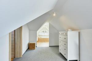 an attic bedroom with a white dresser and a staircase at Villa Astoria in Świnoujście