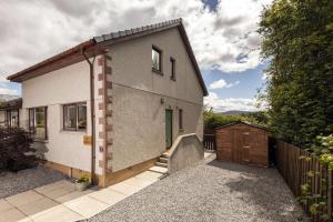 a small house with a fence and a driveway at Hillside Balcony in Kingussie