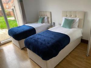 two beds with blue sheets in a room with a window at Amazing 4 bed Contractor hub in Nuneaton