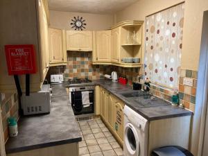 cocina con armarios de madera y horno con fogones en Amazing 4 bed Contractor hub, en Nuneaton