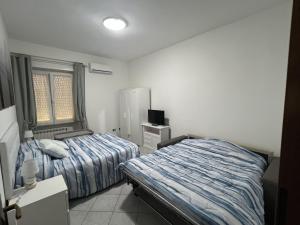 1 dormitorio con 2 camas y TV. en Bed and Breakfast Mare Blu, en Civitavecchia