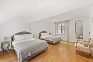 2 camas num quarto branco com pisos em madeira em Hububb Luxury Knightsbridge House em Londres