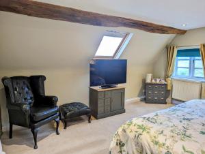 a bedroom with a bed and a chair and a tv at Worralls Grove Guest Farm House in Bewdley