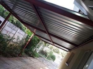 an open garage door with a metal roof at Heila & Glen's Cottage in Bloemfontein