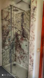 uma casa de banho com um chuveiro e uma parede em mármore. em Torre dei Pirati em Letojanni
