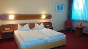 バンベルクにあるHotel Berliner Ringの白いベッド1台(木製ヘッドボード付)が備わるベッドルーム1室が備わります。