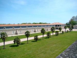 a row of palm trees in a park with a building at T2 meublé pour curistes, vacanciers et stagiaires in Rochefort