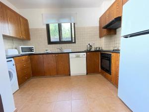 a kitchen with wooden cabinets and white appliances at Villa Med-Sunset in Kissonerga