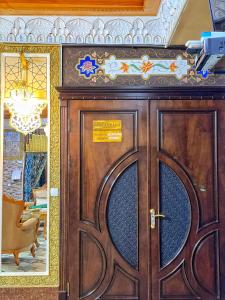 una puerta de madera con un cartel en la parte superior en Hotel Nurafshon Boutique, en Bukhara