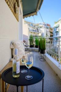 een fles wijn en twee glazen op een tafel op een balkon bij Boho Luxury 2 BR Apartment, Acropolis Museum View in Athene