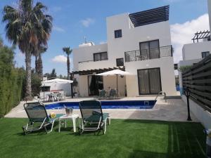 une maison avec une cour dotée de chaises et d'une piscine dans l'établissement Villa Med-Sunset, à Kissonerga